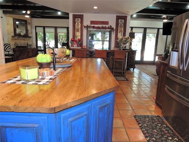 kitchen with french doors, butcher block countertops, stainless steel fridge, ceiling fan, and a fireplace