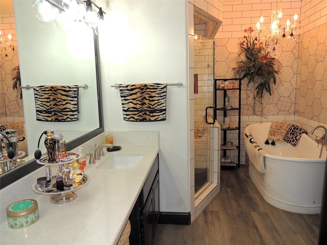 bathroom featuring vanity, a notable chandelier, wood-type flooring, and separate shower and tub