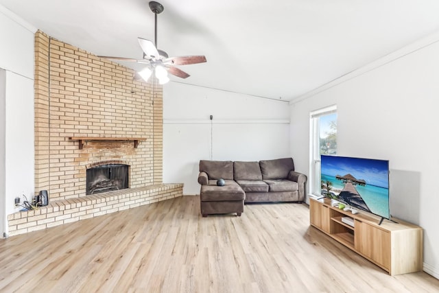 living room with light wood-type flooring, ornamental molding, vaulted ceiling, ceiling fan, and a fireplace