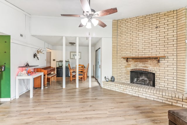 living room with ceiling fan, light hardwood / wood-style floors, and a brick fireplace