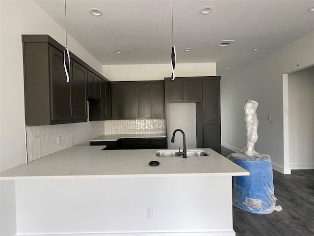 kitchen featuring dark wood-type flooring, decorative backsplash, sink, and pendant lighting