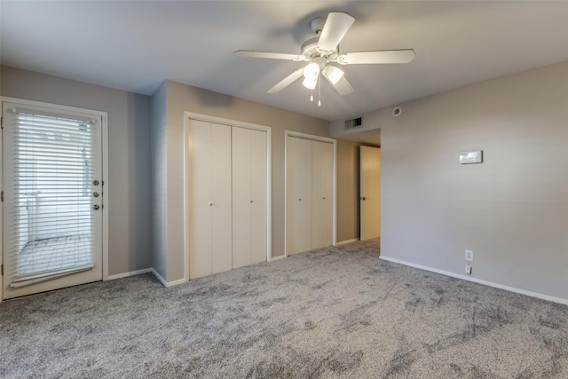 unfurnished bedroom with carpet flooring, ceiling fan, and multiple closets