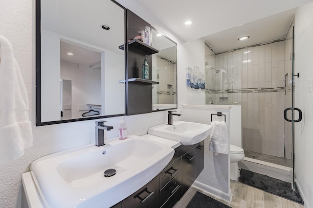 bathroom with hardwood / wood-style floors, vanity, toilet, and a shower with door