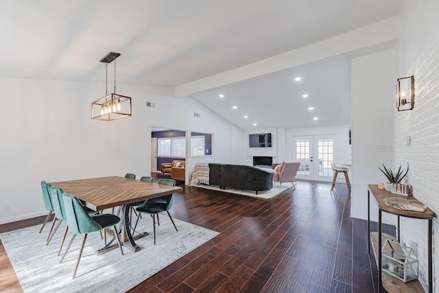 dining area with vaulted ceiling with beams, hardwood / wood-style floors, french doors, and a brick fireplace