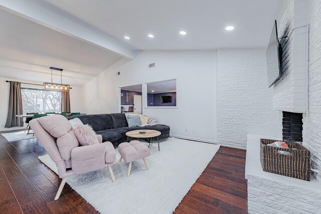 living room with lofted ceiling with beams, a fireplace, wood-type flooring, and a notable chandelier