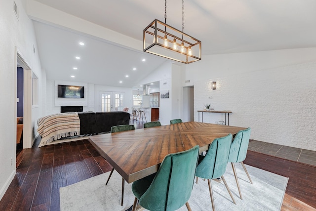 dining room featuring wood-type flooring, a large fireplace, and lofted ceiling