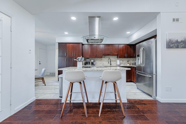 kitchen featuring stainless steel refrigerator with ice dispenser, island range hood, a kitchen island, and hardwood / wood-style floors