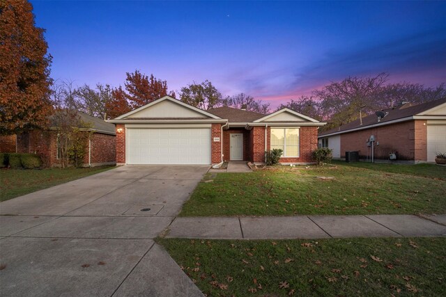 ranch-style house featuring a yard, central AC unit, and a garage