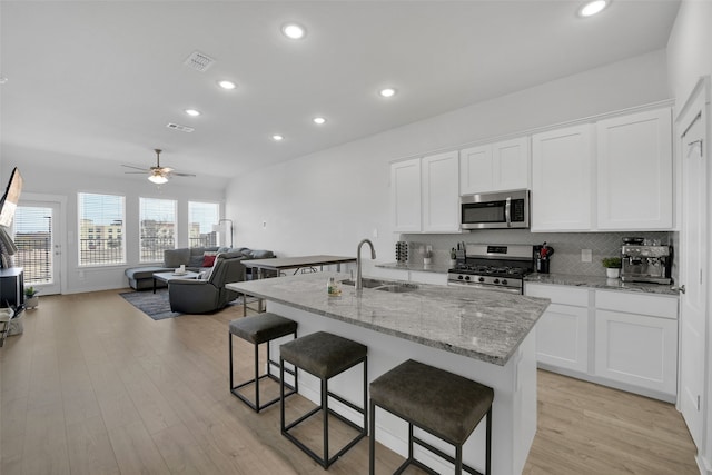 kitchen featuring white cabinets, sink, appliances with stainless steel finishes, and an island with sink