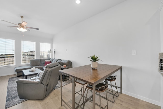 dining area with ceiling fan, light hardwood / wood-style floors, and vaulted ceiling