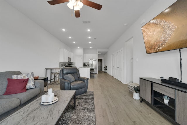 living room featuring ceiling fan and light hardwood / wood-style floors