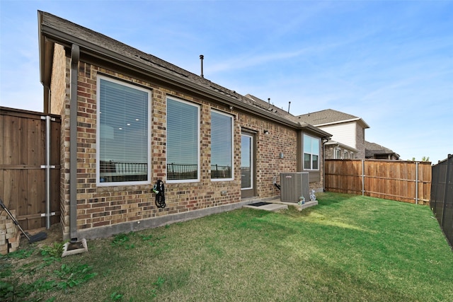 rear view of property with central AC unit and a yard