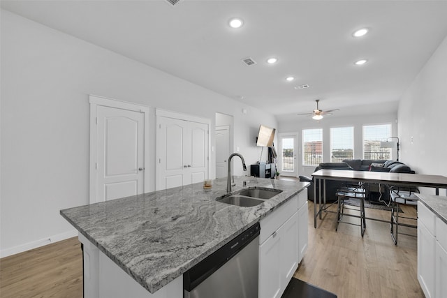 kitchen featuring white cabinetry, stainless steel dishwasher, a center island with sink, and sink