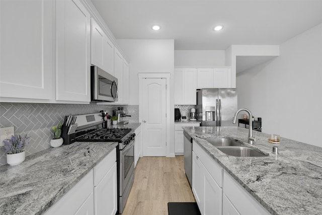 kitchen with white cabinets, stainless steel appliances, light hardwood / wood-style flooring, and sink