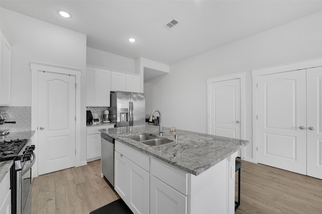 kitchen featuring sink, light wood-type flooring, light stone counters, white cabinetry, and stainless steel appliances