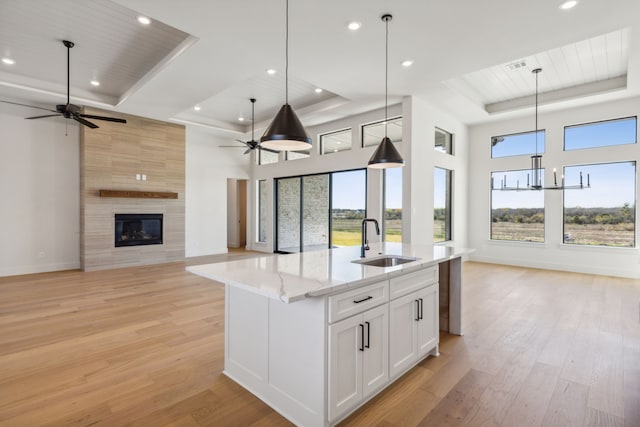 kitchen featuring a tray ceiling, white cabinetry, hanging light fixtures, and sink