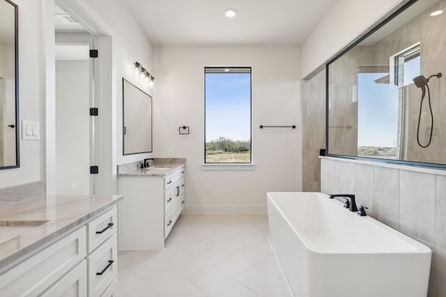 bathroom with a bathing tub, vanity, a healthy amount of sunlight, and tile patterned flooring