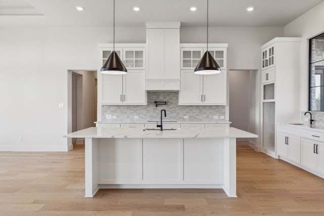 kitchen featuring light stone countertops, pendant lighting, and sink