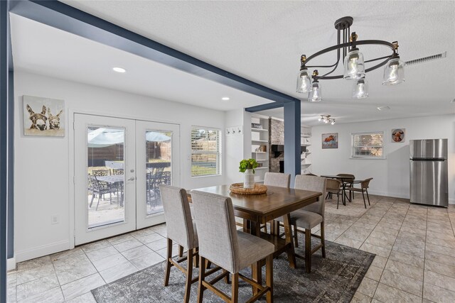 dining area featuring french doors, a chandelier, and a textured ceiling