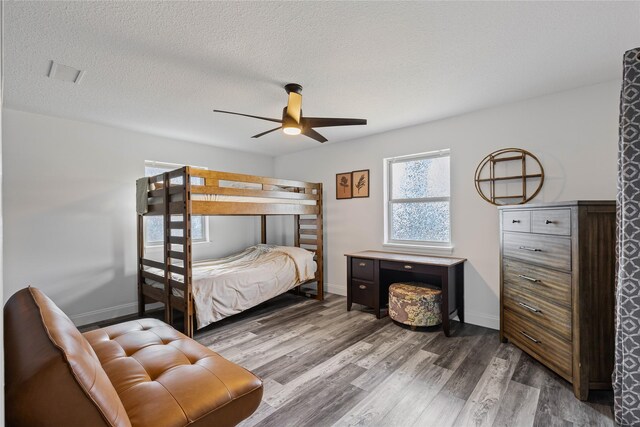 bedroom featuring ceiling fan, wood-type flooring, and a textured ceiling