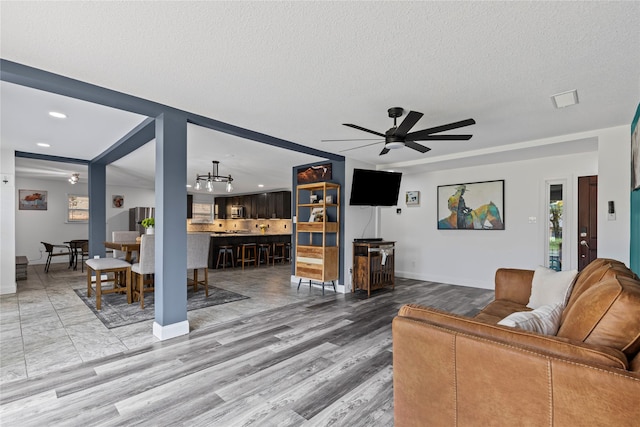 living room featuring ceiling fan, wood-type flooring, and a textured ceiling