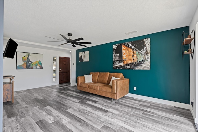 living room with ceiling fan, a textured ceiling, and hardwood / wood-style flooring