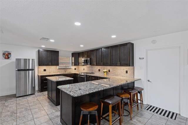 kitchen with light stone countertops, a breakfast bar, and appliances with stainless steel finishes