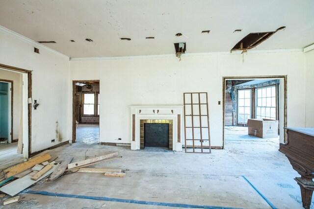 unfurnished living room featuring a healthy amount of sunlight, crown molding, and a tiled fireplace