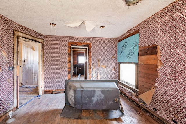 interior space with wood-type flooring, a textured ceiling, and a wood stove