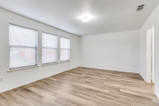 unfurnished room featuring light wood-style floors, visible vents, and baseboards