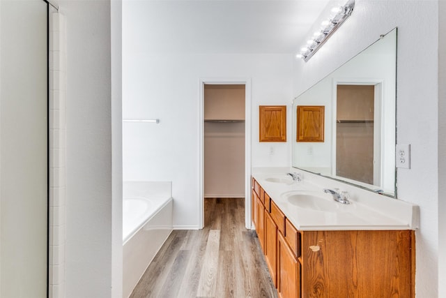 bathroom with a tub to relax in, vanity, and hardwood / wood-style flooring