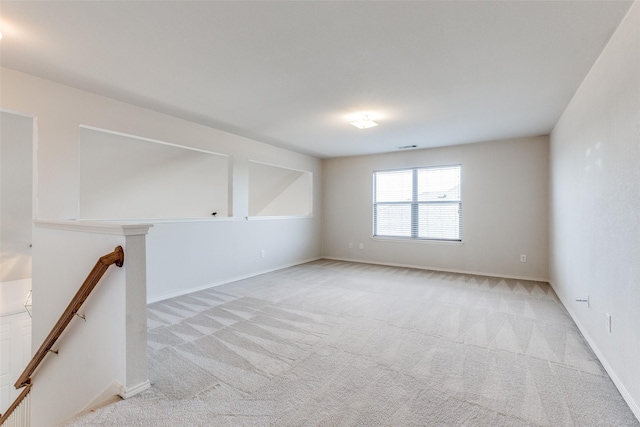 empty room featuring baseboards and light colored carpet