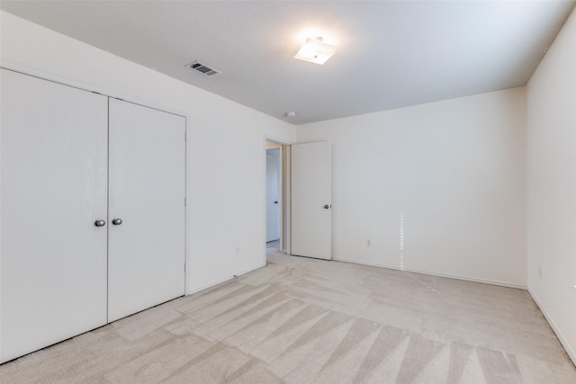 unfurnished bedroom with a closet and light colored carpet