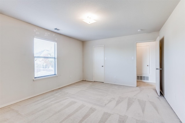 unfurnished bedroom with a closet, light colored carpet, and a textured ceiling