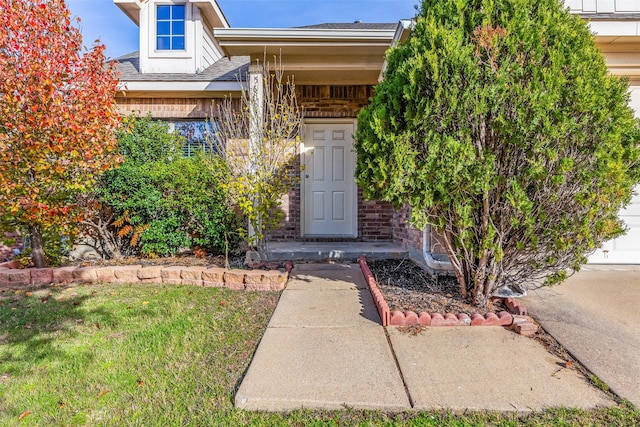 entrance to property featuring a shingled roof and a yard