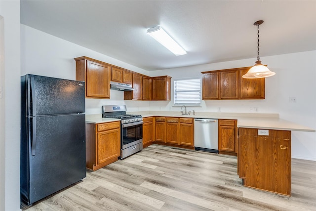 kitchen with pendant lighting, sink, light wood-type flooring, kitchen peninsula, and stainless steel appliances