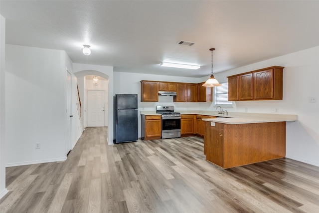 kitchen with arched walkways, visible vents, freestanding refrigerator, stainless steel gas stove, and a peninsula