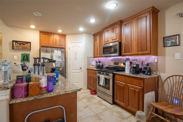 kitchen featuring tasteful backsplash, light stone countertops, light tile patterned floors, and stainless steel appliances