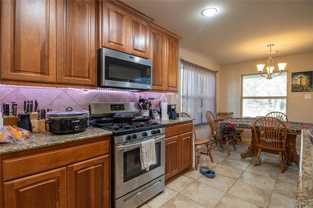 kitchen featuring pendant lighting, a notable chandelier, backsplash, and appliances with stainless steel finishes