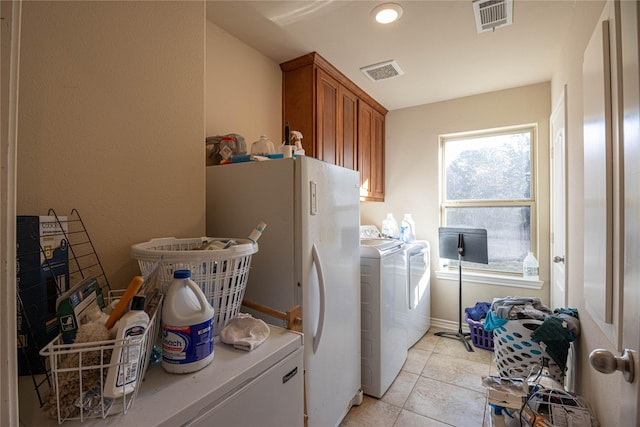 clothes washing area with washer and clothes dryer, cabinets, and light tile patterned floors