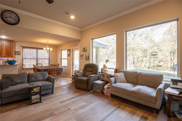 living room with a chandelier, light wood-type flooring, and crown molding