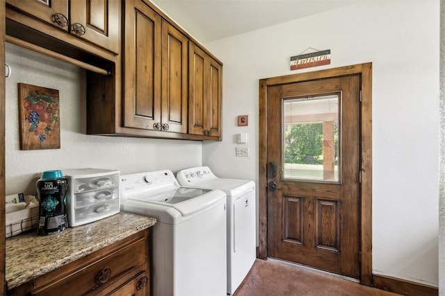 clothes washing area featuring washer and clothes dryer and cabinets