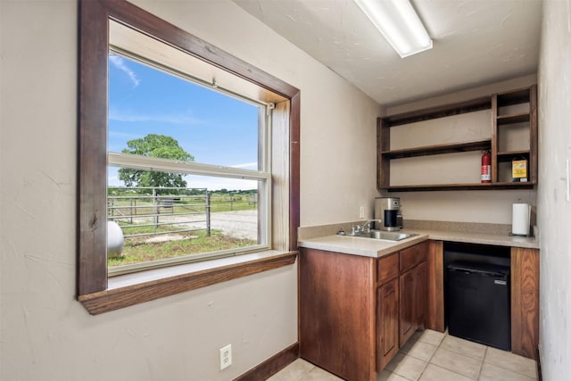 kitchen featuring sink, light tile patterned floors, and black dishwasher