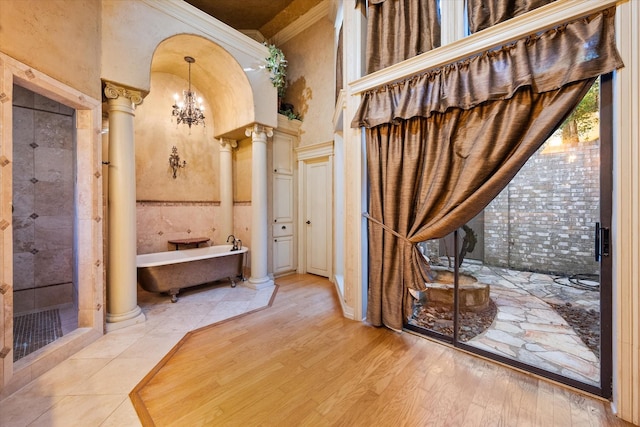 bathroom with decorative columns, a chandelier, a bathtub, and a towering ceiling