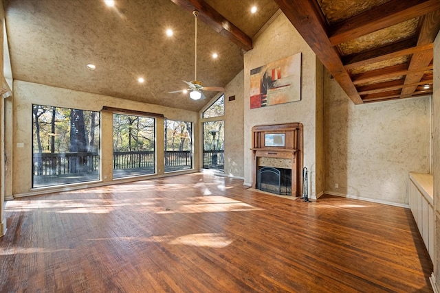 unfurnished living room with ceiling fan, beamed ceiling, a high ceiling, and hardwood / wood-style flooring