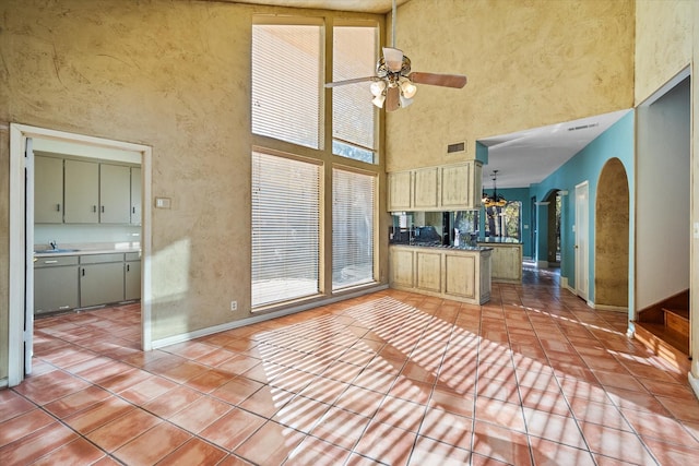 kitchen featuring ceiling fan, tile patterned flooring, and a towering ceiling