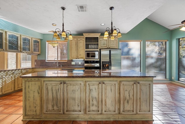 kitchen with backsplash, light tile patterned floors, stainless steel appliances, and a kitchen island