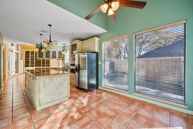 kitchen with a center island, hanging light fixtures, appliances with stainless steel finishes, light tile patterned floors, and cream cabinets