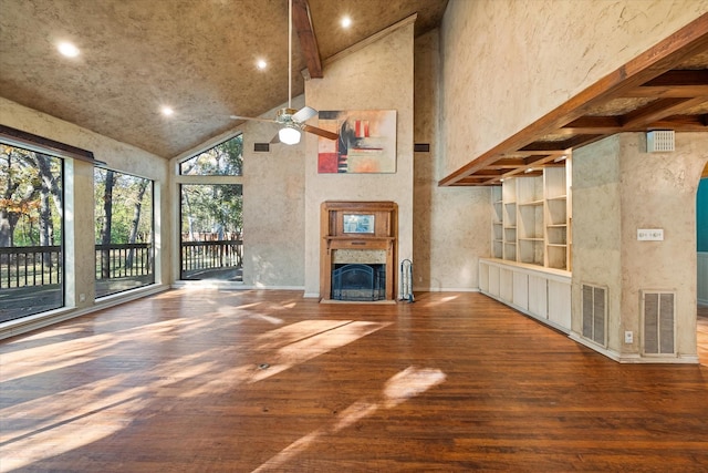 unfurnished living room featuring hardwood / wood-style flooring, ceiling fan, built in features, a towering ceiling, and beamed ceiling