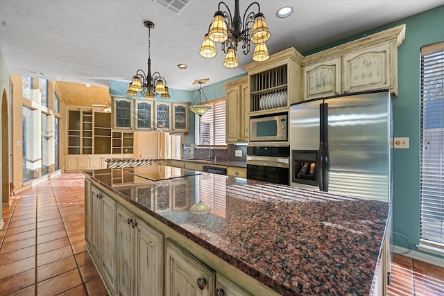 kitchen featuring decorative light fixtures, tile patterned floors, stainless steel appliances, sink, and a notable chandelier